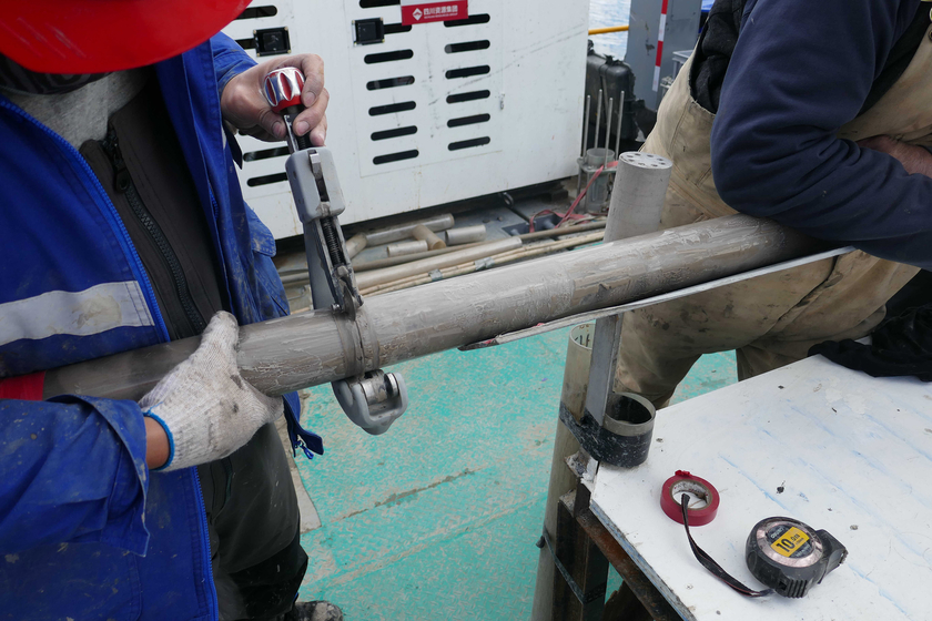 Les carottes de sédiments dans des tubes en plastique (liners) sont encore divisées en morceaux d'environ 1 m de long sur la plate-forme de carottage. Au total, l'équipe a foré 1300 mètres de sédiments. (Photo : Eawag)