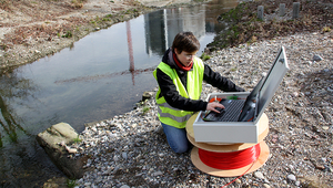 Anne-Marie Kurth at the field site on the restored Chriesbach stream (Canton Zurich): in the method developed by the Eawag researcher, a fibre-optic cable buried in the streambed is used for temperature measurement. (Foto: Andri Bryner)