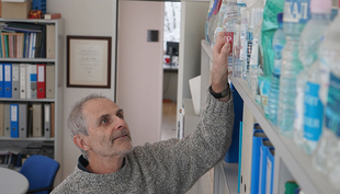 Prof. Urs von Gunten pictured in his office at Eawag with a collection of drinking water samples from all over the world. (Photo: Andri Bryner)