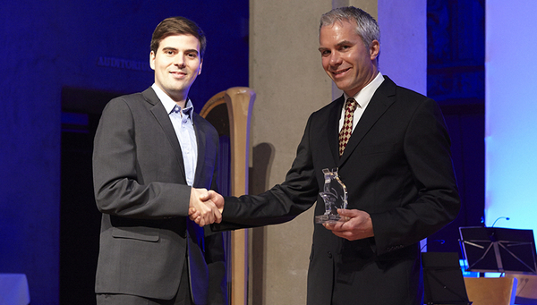 Kay Schaller, representative of VSETH, presents the Golden Owl to Eawag researcher Martin Ackermann.  Rights: Giulia Marthaler; ETH Zürich